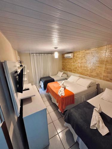 a hotel room with two beds and a flat screen tv at Pousada do Golfinho Fernando de Noronha in Fernando de Noronha