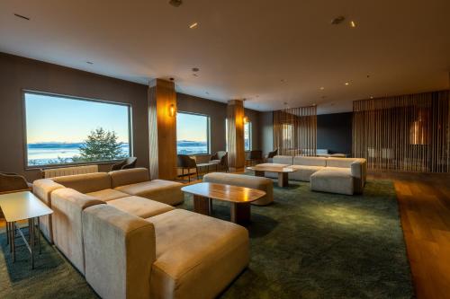 a living room with couches and tables and a large window at Los Acebos Ushuaia Hotel in Ushuaia