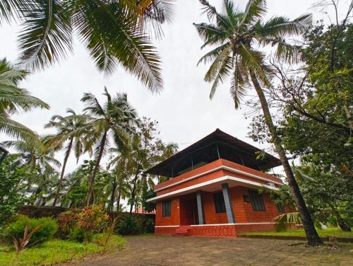 a small house with palm trees in front of it at THEERTHAMKARA Staycation in Nīleshwar