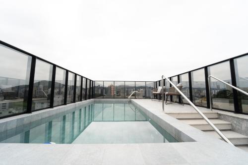 einen Pool auf einem Gebäude mit Fenstern in der Unterkunft Lofts amplos e sofisticados a 600m da Vila Germânica in Blumenau