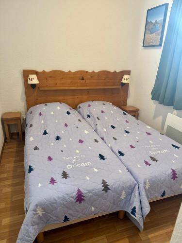 a bed with a blue comforter with butterflies on it at Les granges d'Arvieux vue sur le Queyras in Arvieux
