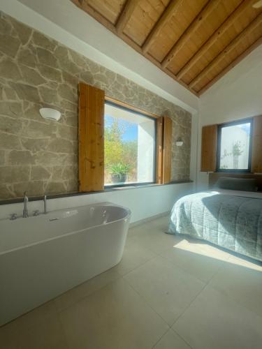 a bedroom with a tub and a bed and a window at B&B Quinta a Fonte Tavira - Adults Only in Tavira