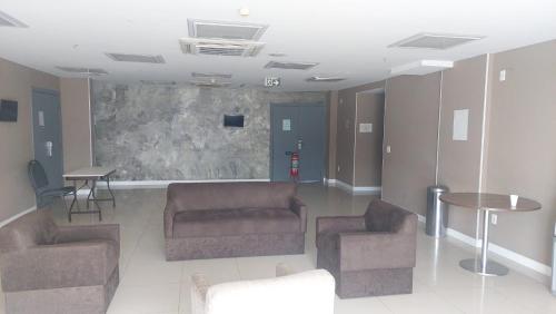 a waiting room with couches and tables in a building at Flat suite morador Hotel in Nova Iguaçu