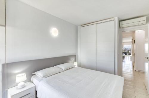 a white bedroom with a white bed and a mirror at Apartamento con vistas a mar y canal. Empuriabrava in Empuriabrava