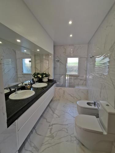 ein weißes Badezimmer mit zwei Waschbecken und einer Toilette in der Unterkunft Luxury 3 bedroom Villa with Private Pool in Cabanas de Tavira