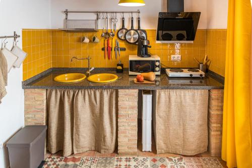 eine Küche mit gelben Fliesen und einer Theke mit zwei Spülbecken in der Unterkunft Casa rural La Artística, alojamiento y arte in Fuenteheridos