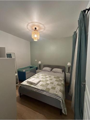 une chambre avec un lit et un lustre dans l'établissement Appartement T2 Paray vieille poste, à Paray-Vieille-Poste