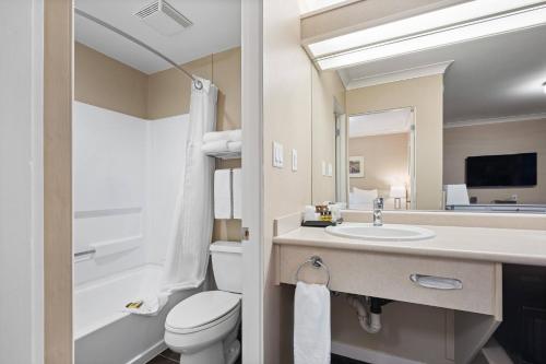 a bathroom with a sink and a toilet and a mirror at Glenwood Inn & Suites in Trail