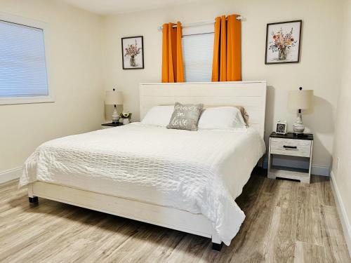 a bedroom with a white bed with an orange curtain at Country Welcome in Micanopy