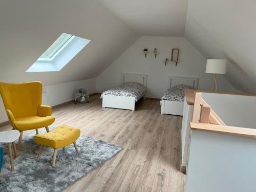 a attic room with two beds and a yellow chair at Clair Matin - Maison avec jardin privatif in Crécy-en-Ponthieu
