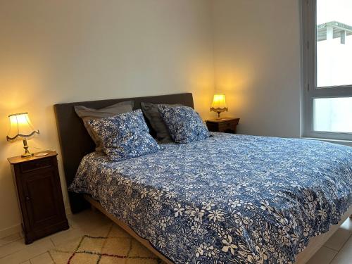 a bedroom with a bed with a blue comforter and two lamps at Charming flat just outside Paris w free Private Parking in Saint-Ouen