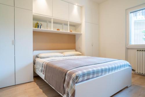 a white bedroom with a bed and a window at La casa di Bella - con Piscina in Padenghe sul Garda