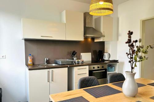 a kitchen with white cabinets and a table with chairs at Großzügige Wohnung - 6 Personen-3 Schlafzimmer- Parkplatz- Waschmaschine-2 Balkone in Wolfsburg