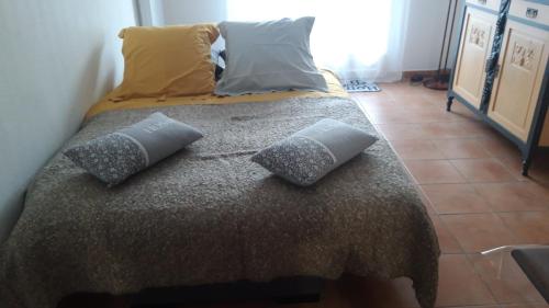 Una cama con dos almohadas encima en una habitación. en "Les Bastides" Appartement tout confort, parking privé piscine, en Lorgues