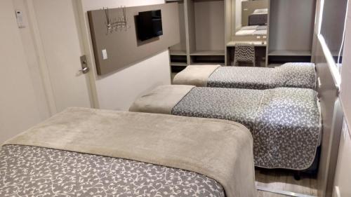 a group of three beds in a room at Hotel Palmas Executivo in Balneário Camboriú