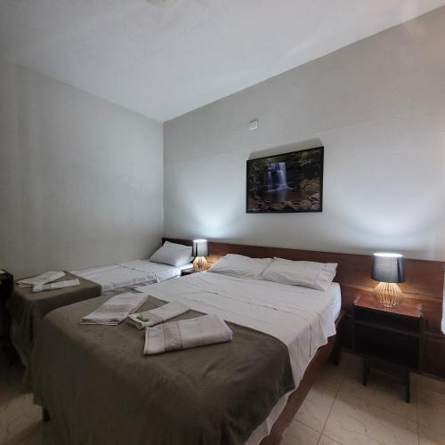 two beds in a hotel room with two lamps and avertisement at Pousada Chapada Equilibrio in Chapada dos Guimarães