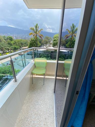 a balcony with two green chairs on a cruise ship at Hotel Plaza Mayor Itagui in Itagüí