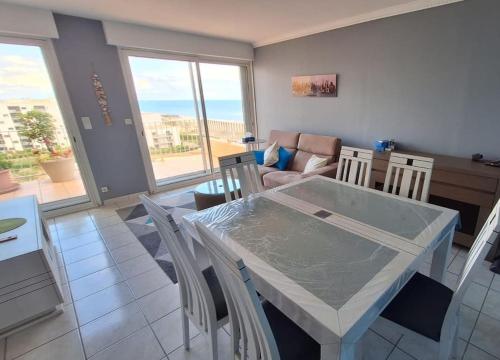 un salon avec une table, des chaises et un canapé dans l'établissement T3 Duplex Vue mer accès Plage, à Dosse Gros