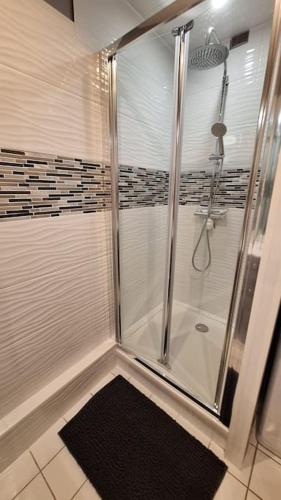 une douche avec une porte vitrée dans une salle de bain dans l'établissement T3 Duplex Vue mer accès Plage, à Dosse Gros