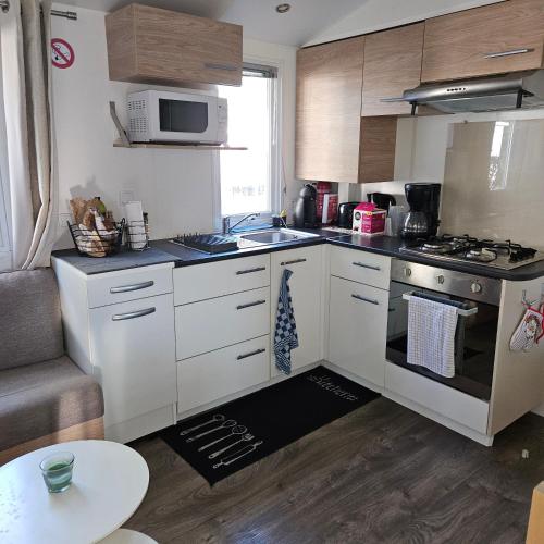 une cuisine avec des armoires blanches et un four à plaques de cuisson dans l'établissement mobilhome, à Valras-Plage