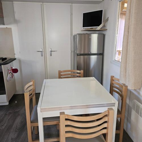 Il comprend une cuisine équipée d'une table blanche et d'un réfrigérateur. dans l'établissement mobilhome, à Valras-Plage