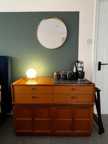 a dresser with a lamp and a mirror on top at Luxury Room in the New Forest in Eling