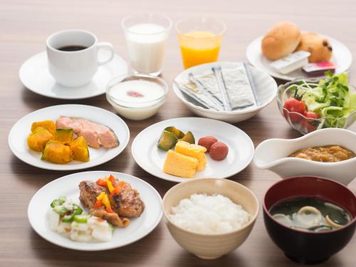a wooden table topped with plates of food and drinks at Sotetsu Fresa Inn Chiba Kashiwa in Kashiwa