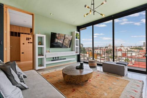 a living room with a coffee table and large windows at Espectacular PENTHOUSE en Centro de Puebla in Puebla