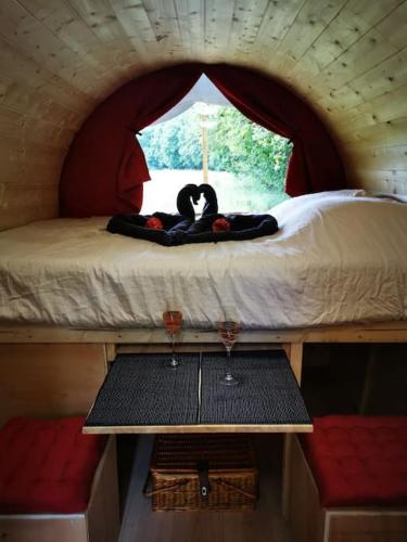 Cette chambre comprend un lit et une table avec deux verres à vin. dans l'établissement La roulotte des nuits étoilées du moulin, à Sainte-Orse
