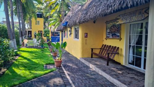 a yellow building with a bench in front of it at Hotel Cafe del Sol in Monterrico