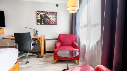 Habitación con silla roja y escritorio. en Hôtel Lindbergh par JARO, en Quebec