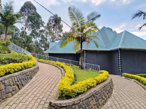 a walkway with yellow flowers in front of a blue building at EAR KEN BARHAM GUESTHOUSE in Rwumba