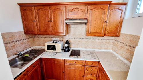 a kitchen with wooden cabinets and a microwave at Jokai sor II Apartman in Hajdúszoboszló