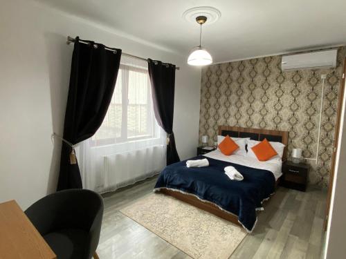 a bedroom with a bed with orange pillows and a window at Cazare Pensiune La Bozi in Utvin