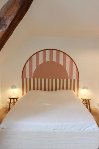 - un lit avec une tête de lit rayée dans une chambre dans l'établissement Le Petit Clos au coeur de Puligny-Montrachet, à Puligny-Montrachet
