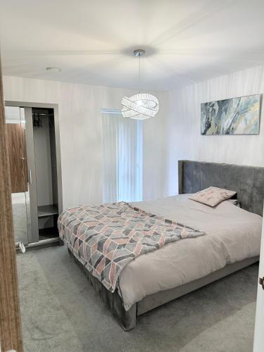 a bedroom with a large bed and a chandelier at Sorbus - Flat in West Thurrock