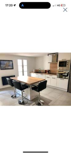 une cuisine avec une table en bois et deux chaises noires dans l'établissement Appartement standing, à Perpignan