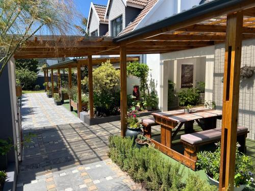 a patio with a wooden pergola with a table and benches at Pelican Lodge Guesthouse in Sedgefield