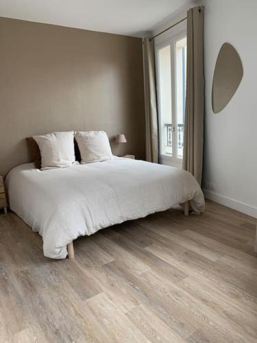 une chambre avec un grand lit et une grande fenêtre dans l'établissement Charmant 2 pièces rénové parc des expositions porte de Versailles, à Vanves