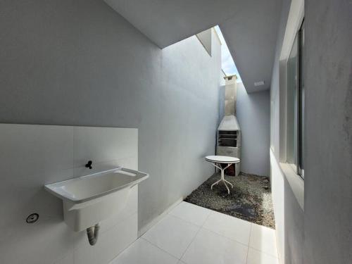 a white bathroom with a sink and a stool at Casa de praia com wi-fi in Barra Velha