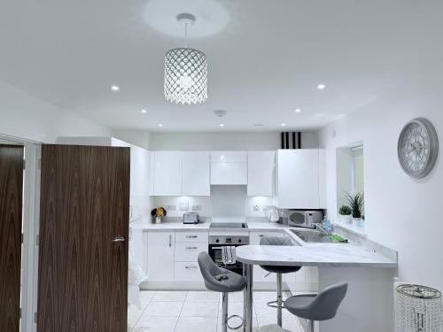 a kitchen with white cabinets and a table and chairs at Sorbus - Flat in West Thurrock