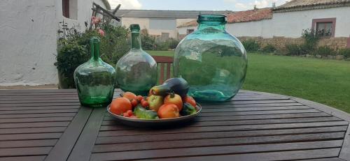 a bowl of fruit on a table with two glass vases at Hotel Rural El Cielo Entejado in Tejado