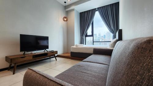 a living room with a couch and a tv and a bed at Opus Residences Kuala Lumpur by Infini Suites in Kuala Lumpur