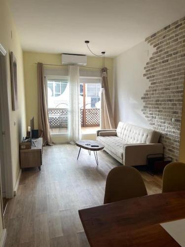 a living room with a white couch and a brick wall at Apartamento céntrico con terraza y parking in Huelva