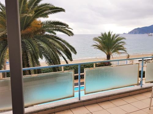 balcón con vistas a la playa y a las palmeras en Hotel Miramare, en Savona