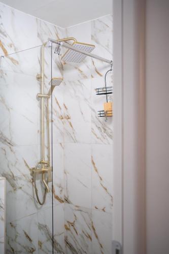 a shower in a bathroom with a marble wall at Zena Apartment in Ocna-Mureşului