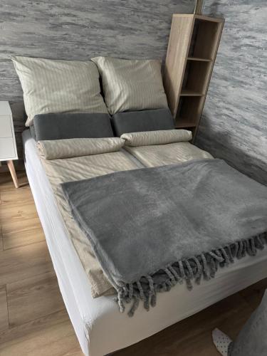 a white bed with a grey blanket on it at Szeged Sunshine Apartman in Szeged
