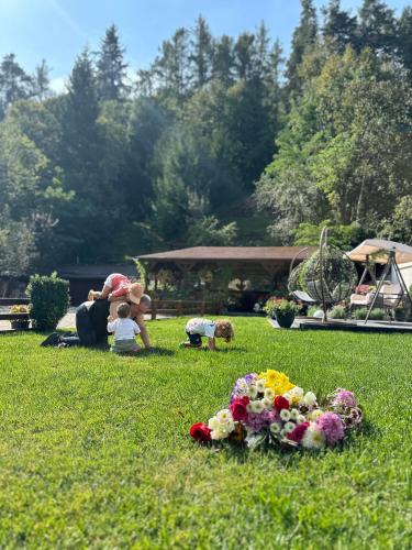 a group of people sitting in the grass with flowers at Pensiunea Domnescu in Sălişte