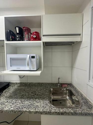 a kitchen counter with a sink and a microwave at Apartamento Smart in São Carlos