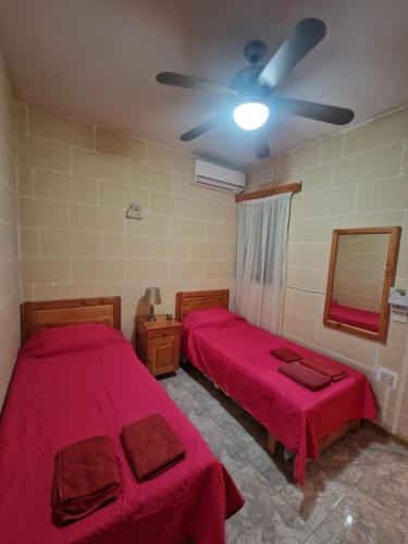 Cette chambre dispose de 2 lits et d'un ventilateur de plafond. dans l'établissement Attard Seafront Apartment 3 in Marsalforn, à Żebbuġ